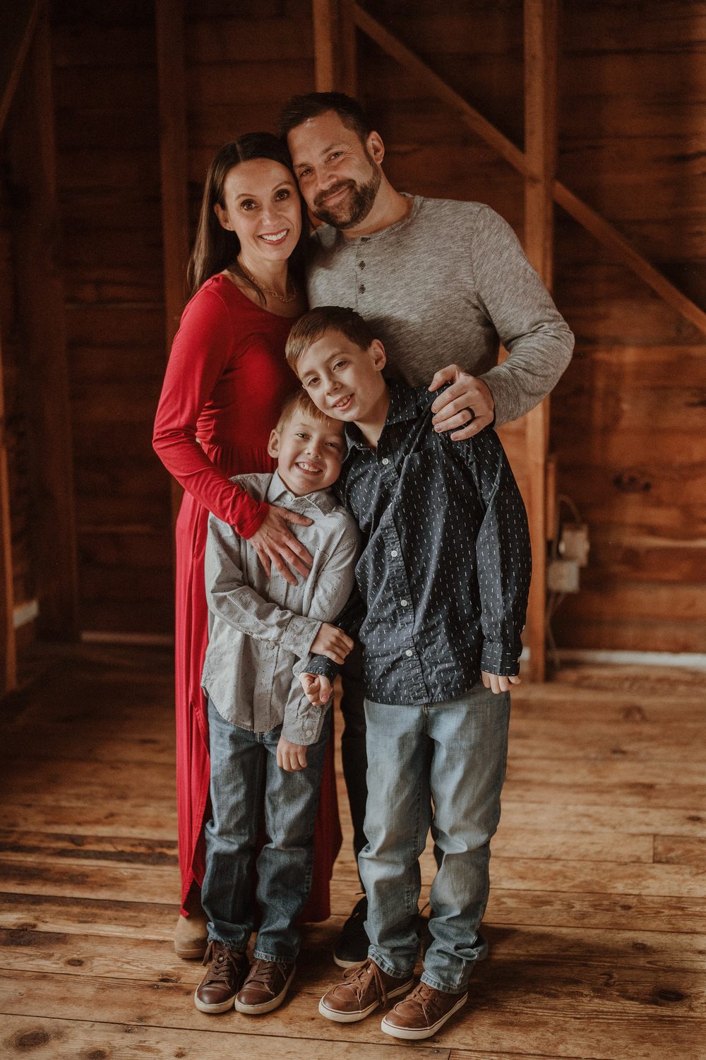Michael Defoe with his wife and their two sons, standing together in a wood-paneled barn